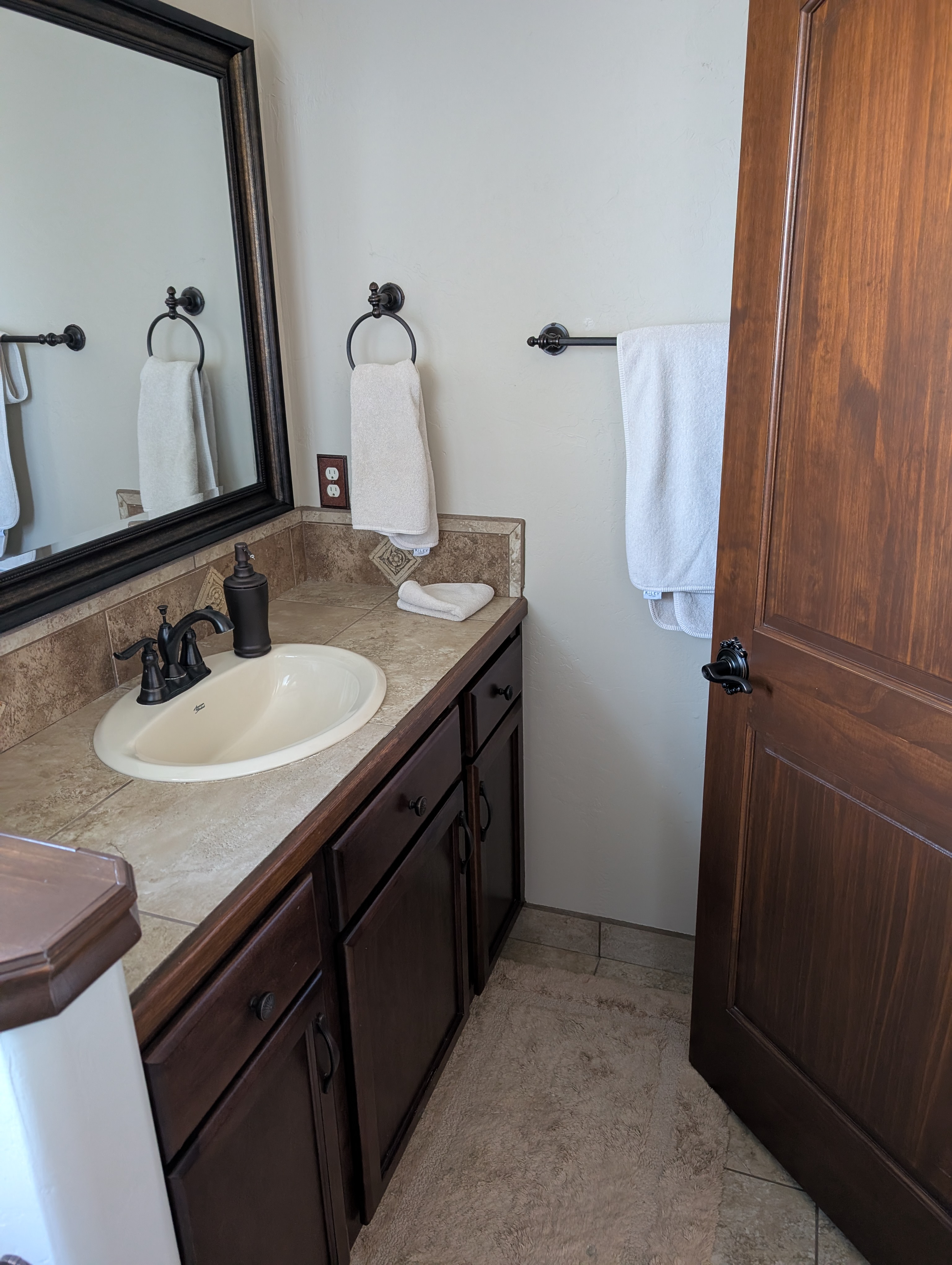 Private bathroom vanity with dark wood cabinets and tile countertop